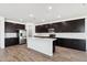 Spacious kitchen featuring dark wood cabinetry, quartz countertops, stainless steel appliances, and an island at 15778 W Cheryl Dr, Waddell, AZ 85355