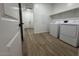 Well-lit laundry room equipped with a washer, dryer, and shelving, plus wood-look tile flooring at 15778 W Cheryl Dr, Waddell, AZ 85355