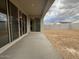 Covered patio with sliding glass doors overlooking a spacious, unfinished backyard at 15778 W Cheryl Dr, Waddell, AZ 85355