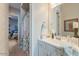 Bright bathroom with white cabinetry, framed mirror, and shower with decorative floral curtain at 15843 S 177Th Ave, Goodyear, AZ 85338