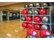 A variety of red and silver exercise balls are organized in a white shelf next to a mirrored wall in the gym at 15843 S 177Th Ave, Goodyear, AZ 85338