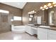 Luxurious bathroom featuring a soaking tub, double sinks, marble countertops, and a walk-in glass shower at 16215 W Indianola Ave, Goodyear, AZ 85395