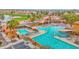 Aerial view of community with pools, palm trees, lounge chairs, desert landscape, and golf course at 16215 W Indianola Ave, Goodyear, AZ 85395