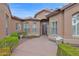 Exterior view of a home's front entrance featuring manicured shrubs and flower pots with arched windows and shutters at 16215 W Indianola Ave, Goodyear, AZ 85395