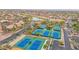 Aerial view of multiple well-maintained tennis courts, surrounded by lush landscaping, enhancing the community's appeal at 16215 W Indianola Ave, Goodyear, AZ 85395