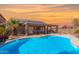 Backyard oasis with sparkling pool, covered patio, desert landscaping, and sunset sky at 17705 N Vera Cruz Ave, Maricopa, AZ 85139