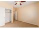 Carpeted bedroom features neutral walls, ceiling fan and closet with doors at 18004 W Palo Verde Ave, Waddell, AZ 85355