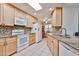 Bright kitchen featuring tile backsplash, white appliances, granite countertops, and wood cabinets at 19481 N Star Ridge Dr, Sun City West, AZ 85375