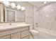 Well-lit bathroom featuring a tub, marble tile, and vanity with a light wood cabinet at 19824 N 94Th Ln, Peoria, AZ 85382