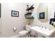 Chic half bathroom featuring a pedestal sink, decorative shelves, and stylish wall art at 2535 E Thornton Ct, Gilbert, AZ 85297