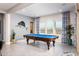 A well-lit game room featuring a classic pool table, stylish curtains, and an adjacent sliding glass door at 2535 E Thornton Ct, Gilbert, AZ 85297