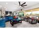 Bright open-concept living room featuring a ceiling fan and access to the backyard and kitchen at 2535 E Thornton Ct, Gilbert, AZ 85297