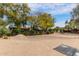 View of the spacious backyard featuring sand landscaping, native plants, and a black metal fence at 38408 N 23Rd Dr, Phoenix, AZ 85086