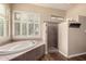 Bathroom featuring a soaking tub near a shuttered window and a walk-in tiled shower with a built-in shelf at 38408 N 23Rd Dr, Phoenix, AZ 85086