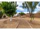 Beautiful landscaped backyard with a pathway leading to a greenhouse amidst mature trees at 38408 N 23Rd Dr, Phoenix, AZ 85086