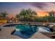 Sparkling pool with desert landscaping and waterfall feature at dusk at 4252 E Desert Sky Ct, Cave Creek, AZ 85331