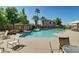 Community pool with lounge chairs, tables, and shady umbrellas under a clear blue sky at 6461 S Kimberlee Way, Chandler, AZ 85249