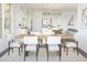 Open concept dining room with a large wooden table, white chairs, and modern light fixtures, bright and airy at 7970 W Griswold Rd, Peoria, AZ 85345