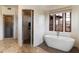 Modern bathroom with a standalone tub, open shower featuring tiled walls, and natural lighting at 9290 E Thompson Peak Pkwy # 470, Scottsdale, AZ 85255