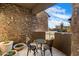 Cozy patio with stone walls, bistro set, potted succulents, and desert views at 9290 E Thompson Peak Pkwy # 470, Scottsdale, AZ 85255