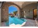 Inviting pool with steps leading into the water, framed by a brick arch and lush greenery for a private retreat at 9290 E Thompson Peak Pkwy # 470, Scottsdale, AZ 85255