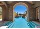 View through stone archway to beautiful blue pool surrounded by manicured landscaping at 9290 E Thompson Peak Pkwy # 470, Scottsdale, AZ 85255