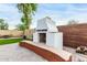 Outdoor kitchen featuring a BBQ, pizza oven, bench seating, brick patio, and decorative tile work at 9295 W Quail Track Dr, Peoria, AZ 85383