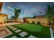 Backyard oasis featuring a putting green, outdoor lighting, and a cozy fireplace, ideal for entertaining at 9295 W Quail Track Dr, Peoria, AZ 85383