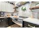 Updated kitchen area showcasing white subway tile, stainless oven/range, floating shelves, and modern white and black cabinets at 9295 W Quail Track Dr, Peoria, AZ 85383