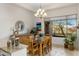 Dining area featuring a modern chandelier, wood table, and bright view to the backyard at 10883 E La Junta Rd, Scottsdale, AZ 85255