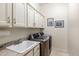 Well-equipped laundry room with cabinetry, a utility sink, and stainless steel washer and dryer at 10883 E La Junta Rd, Scottsdale, AZ 85255