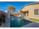 Beautiful pool with a modern water feature, lush landscaping, and covered patio in the backyard at 13568 N 144Th Dr, Surprise, AZ 85379
