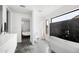 Modern bathroom with a large window, marble accent wall, soaking tub, walk in shower and sleek white vanity at 14025 N 11Th Pl, Phoenix, AZ 85022