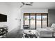 Bright living room showcasing concrete floors, a gray sofa, modern chair and large sliding glass doors to the backyard at 14025 N 11Th Pl, Phoenix, AZ 85022