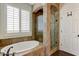 Luxurious bathroom with a soaking tub, glass-enclosed shower, and shuttered window at 14474 W Lexington Ave, Goodyear, AZ 85395