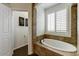 Cozy bathroom featuring a soaking tub, framed fern art, and shuttered window at 14474 W Lexington Ave, Goodyear, AZ 85395