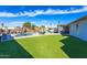 Expansive backyard showcasing lush artificial turf, a sparkling pool, and a covered patio with ample seating at 15802 N 50Th Dr, Glendale, AZ 85306