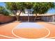 Backyard basketball court with green trees and landscaping in a sunny setting at 16626 W Baden Ave, Goodyear, AZ 85338