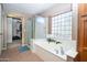 Bathroom featuring a soaking tub, glass block window, and a separate shower enclosure at 16626 W Baden Ave, Goodyear, AZ 85338