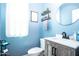 Charming blue bathroom with a gray vanity, round mirror, and decorative wall shelves at 16626 W Baden Ave, Goodyear, AZ 85338