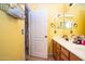 Bathroom featuring double sinks, bright yellow walls, tile floors, and convenient storage options at 16626 W Baden Ave, Goodyear, AZ 85338