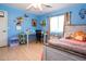 Well-lit bedroom with wood floors, a ceiling fan, and a desk area with creative decorations at 16626 W Baden Ave, Goodyear, AZ 85338