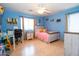 Bright bedroom with wood floors, ceiling fan, and a comfortable bed and a desk area with natural lighting at 16626 W Baden Ave, Goodyear, AZ 85338