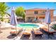 Backyard pool with lounge chairs, umbrellas, patio, and well-maintained landscaping at 16626 W Baden Ave, Goodyear, AZ 85338