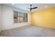 Bright bedroom with large window, plantation shutters, neutral carpet, and a sunny yellow accent wall at 16868 W Earll Dr, Goodyear, AZ 85395
