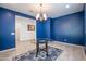 Cozy dining room with bold blue walls, modern chandelier, and open access to the rest of the home at 16868 W Earll Dr, Goodyear, AZ 85395