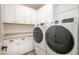 Bright laundry room featuring white cabinets, a countertop, and modern washer and dryer at 16868 W Earll Dr, Goodyear, AZ 85395