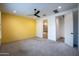Spacious bedroom with neutral carpet leading to the bathroom and featuring a sunny yellow accent wall at 16868 W Earll Dr, Goodyear, AZ 85395
