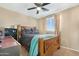 Well-lit bedroom with a decorative bed frame, wooden desk and shelving, ceiling fan, and a patterned throw at 22959 W Cocopah St, Buckeye, AZ 85326