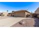 Tan house with two-car garage, desert rock landscaping, and a driveway at 26421 S New Town Dr, Sun Lakes, AZ 85248